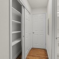 A white pantry with a white door and white shelves.
